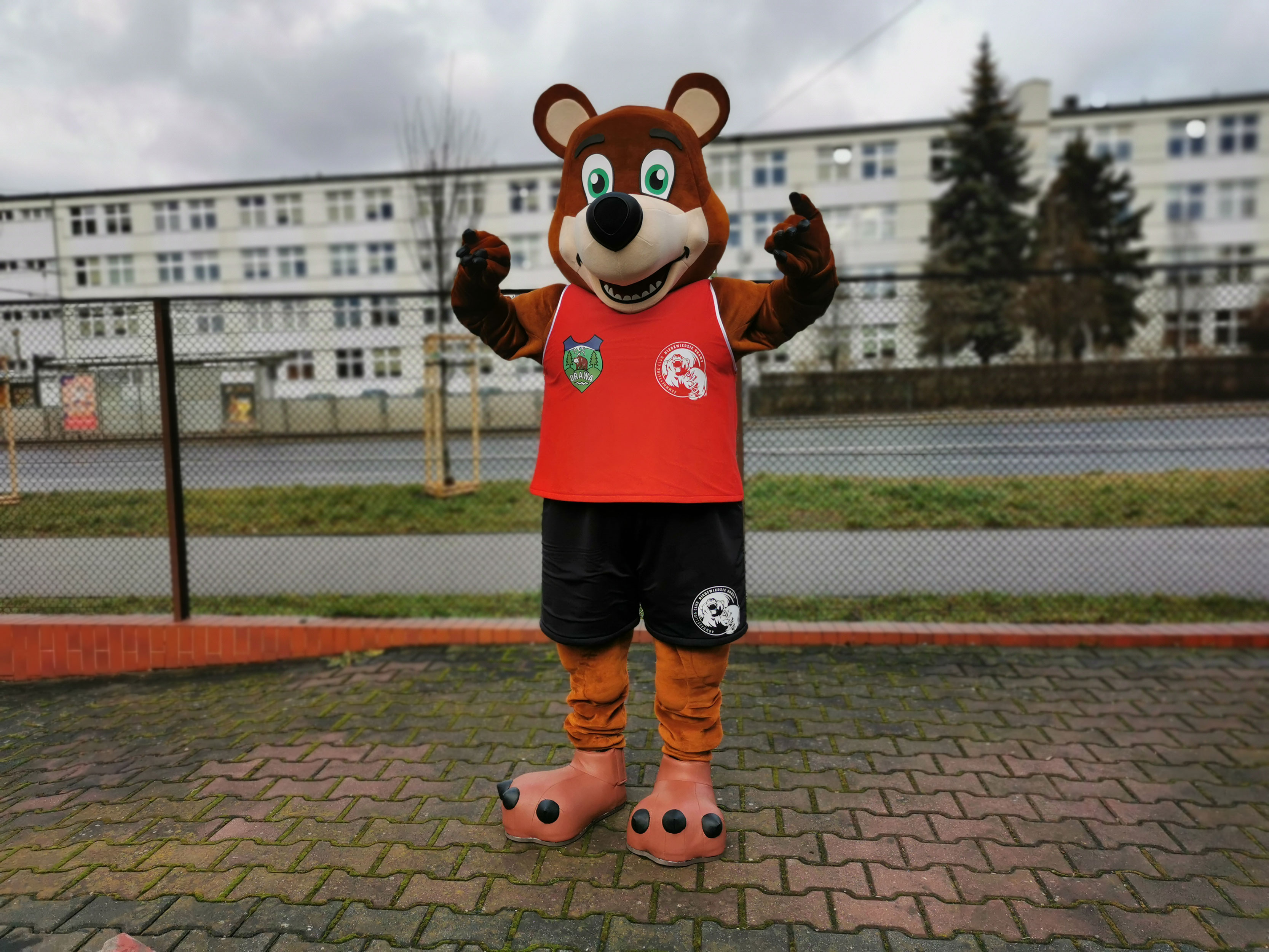 Na fotografii widnieje kostium w postaci misia pozujący do zdjęcia przed siedzibą firmy Elabika